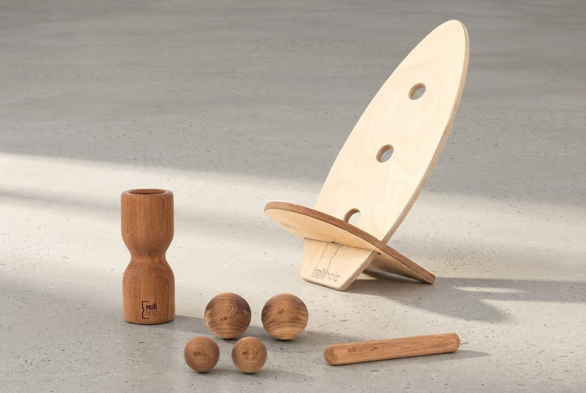 Das rollholz Balance Board Set Groß mit Board, rollholz Pro, Minirolle und Kugeln auf einer Betonfläche