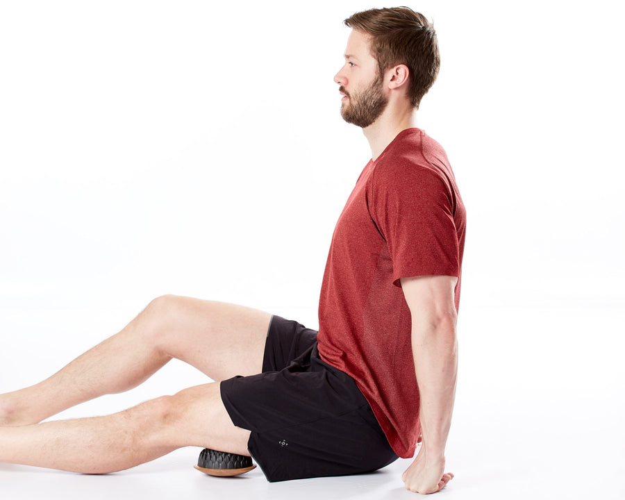 Homme assis qui détend l'arrière de la cuisse avec un dôme Lotus placé sous la cuisse
