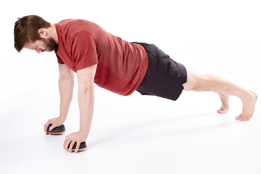 Homme en gainage, les mains sur deux dômes Lotus avec base en bois pour un travail instable