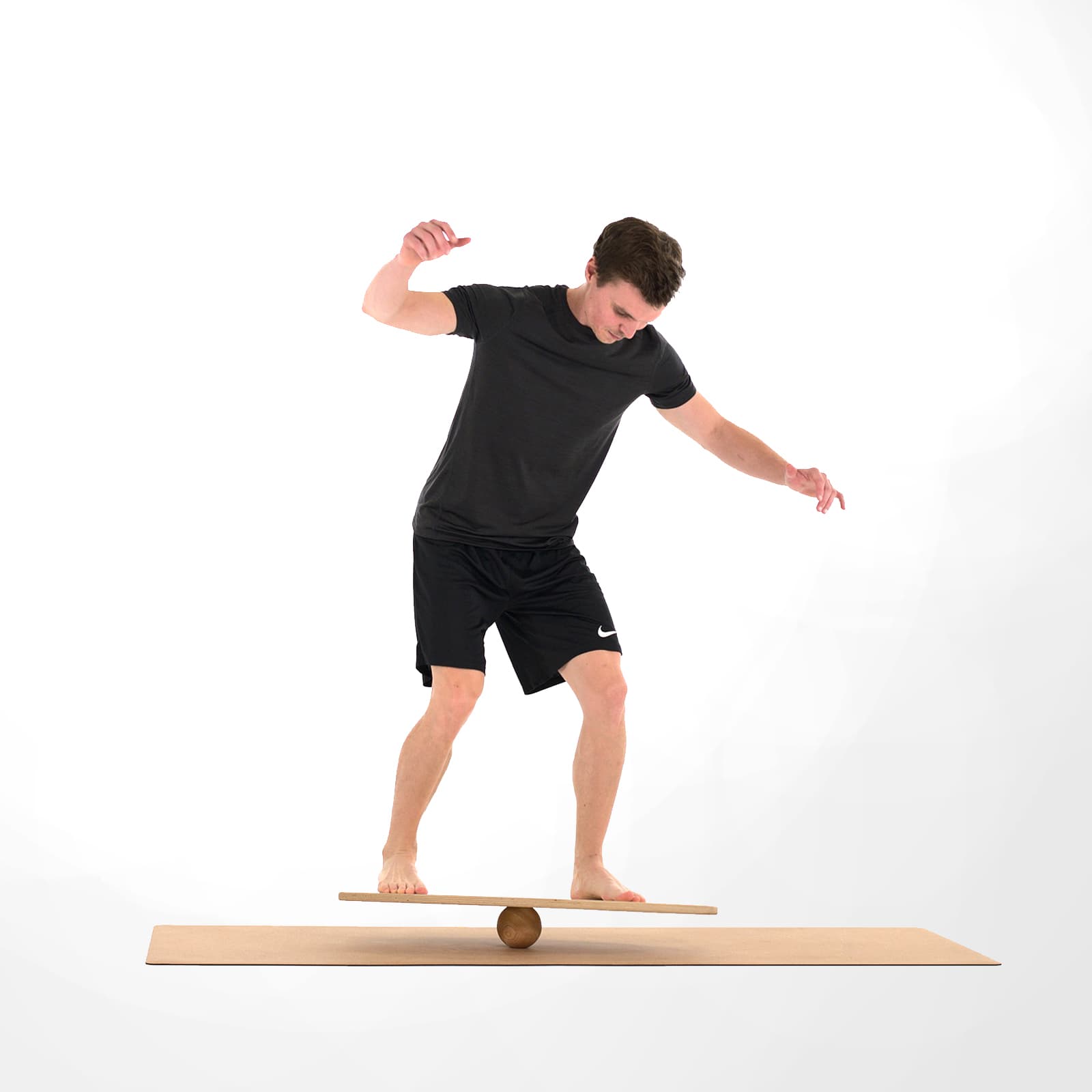 Ein Mann in schwarzer Sportkleidung trainiert barfuß sein Gleichgewicht im aufrechten Stand auf einem rollholz Balanceboard, das extrem instabil auf einer massiven Holzkugel gelagert ist.