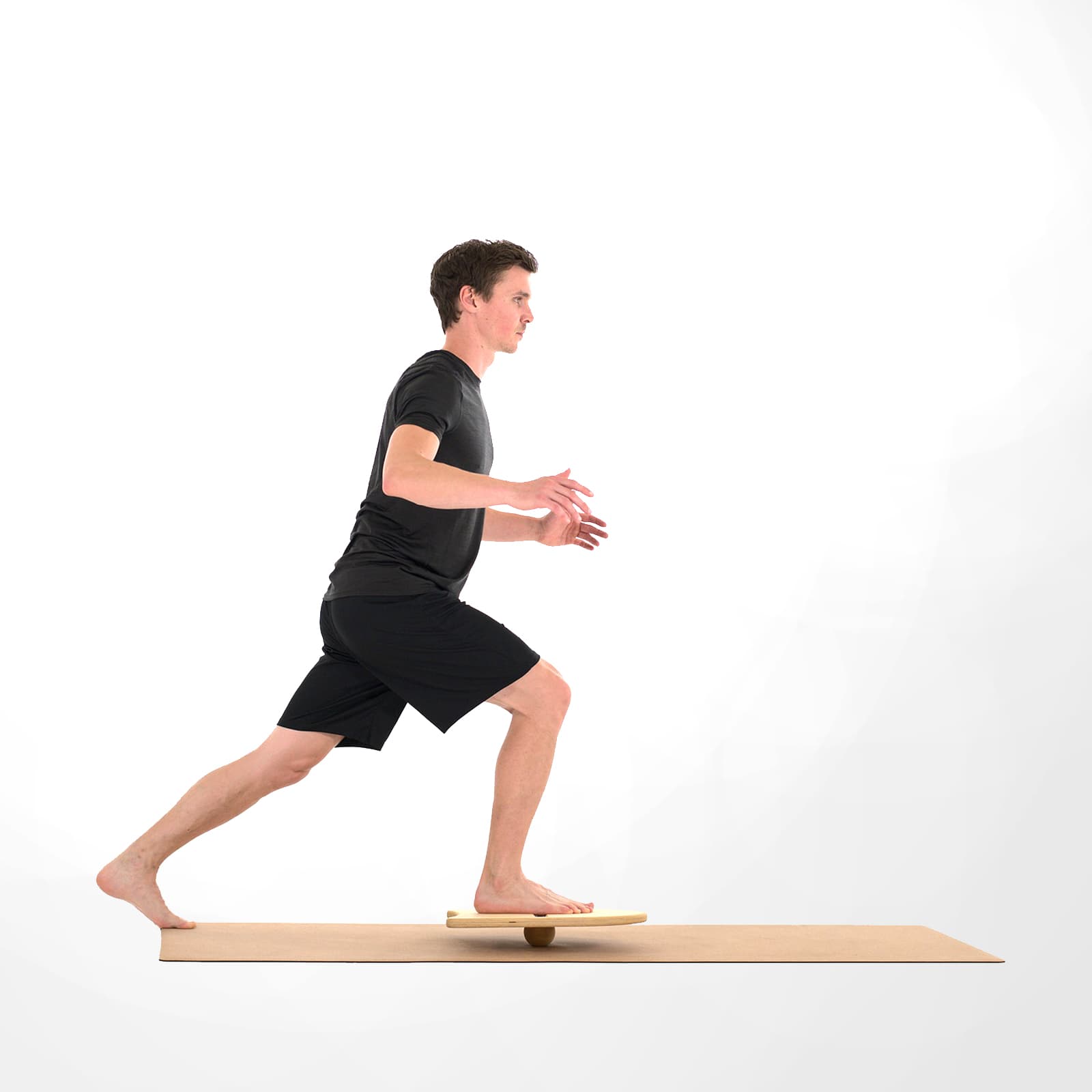 Ein Mann in schwarzer Sportkleidung führt barfuß einen Ausfallschritt (Lunge) auf einer Korkmatte aus, wobei sein vorderer Fuß auf dem kleinen rollholz Balanceboard steht, das instabil auf einer Holzkugel gelagert ist.
