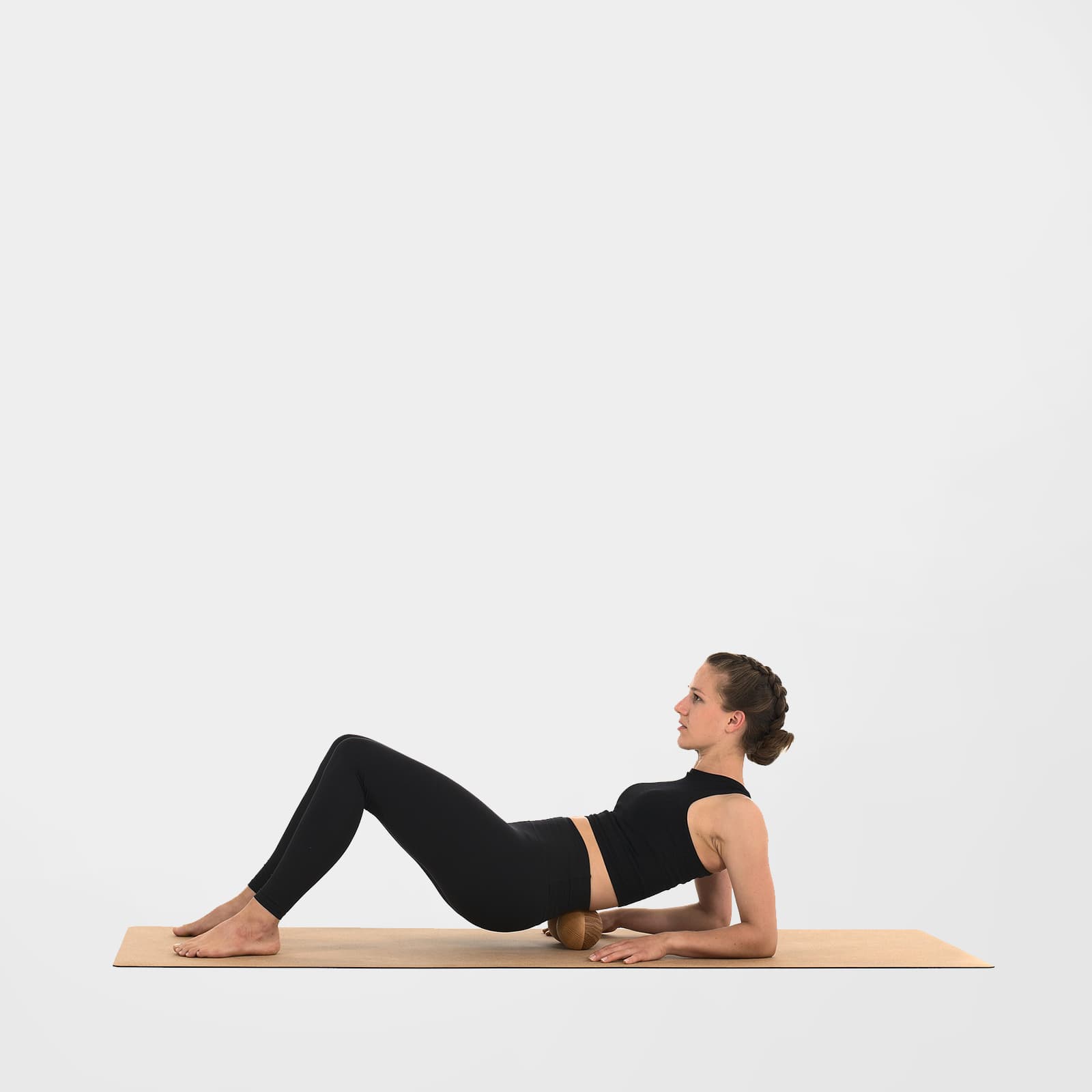 Eine Frau nutzt die rollholz Doppelkugel XL aus Holz auf einer Korkmatte zur Faszienmassage des unteren und mittleren Rückens im Unterarmstütz.