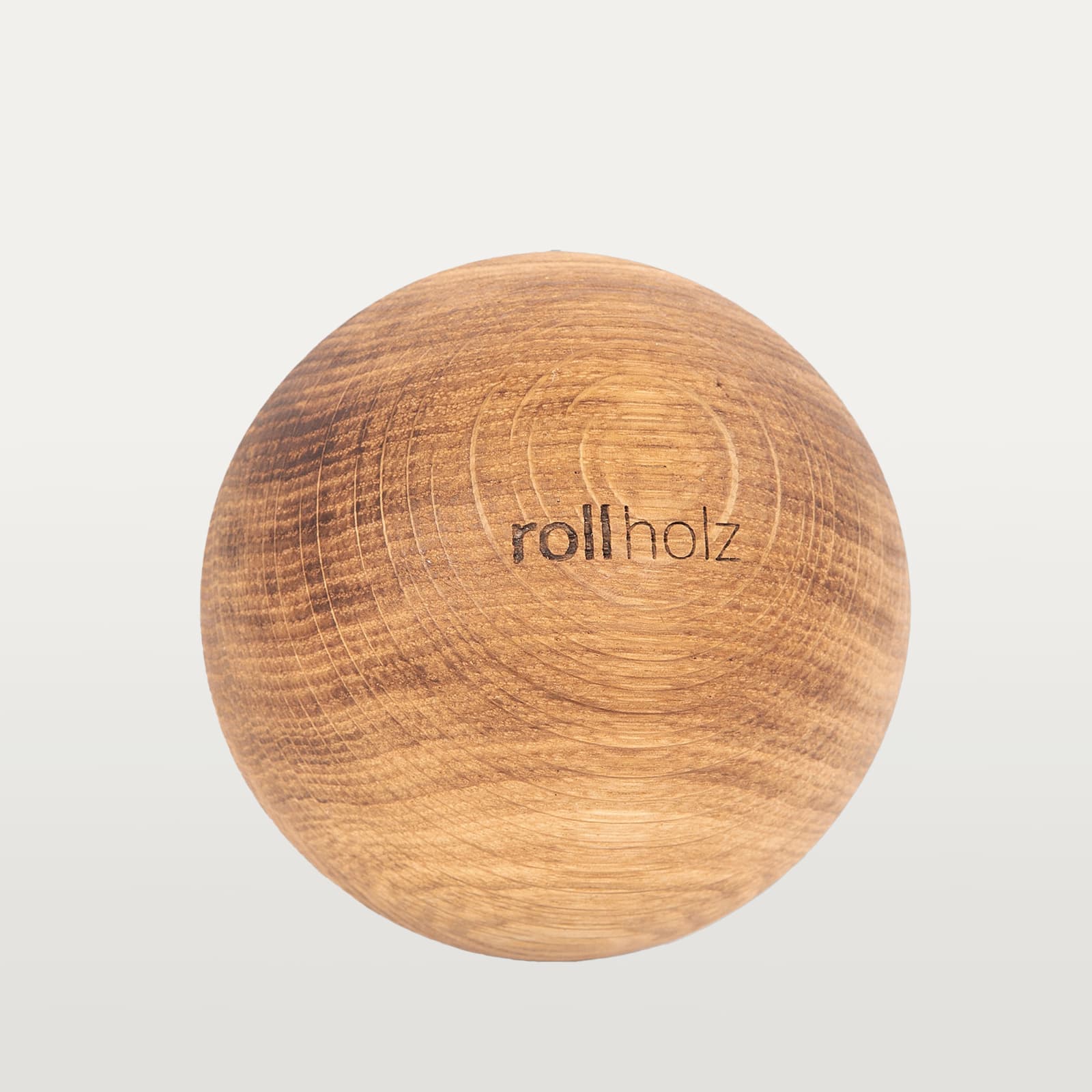 #Holz_Eiche Freigestellte Ansicht einer 10 cm rollholz Faszienkugel aus robustem Eichenholz mit eingelasertem Markenlogo.