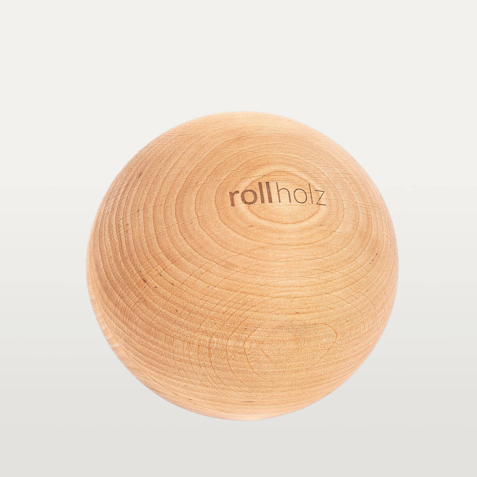 #Holz_Erle Freigestellte Ansicht einer 10 cm rollholz Faszienkugel aus rötlich-warmem Erlenholz mit sauber eingelasertem Markenlogo.