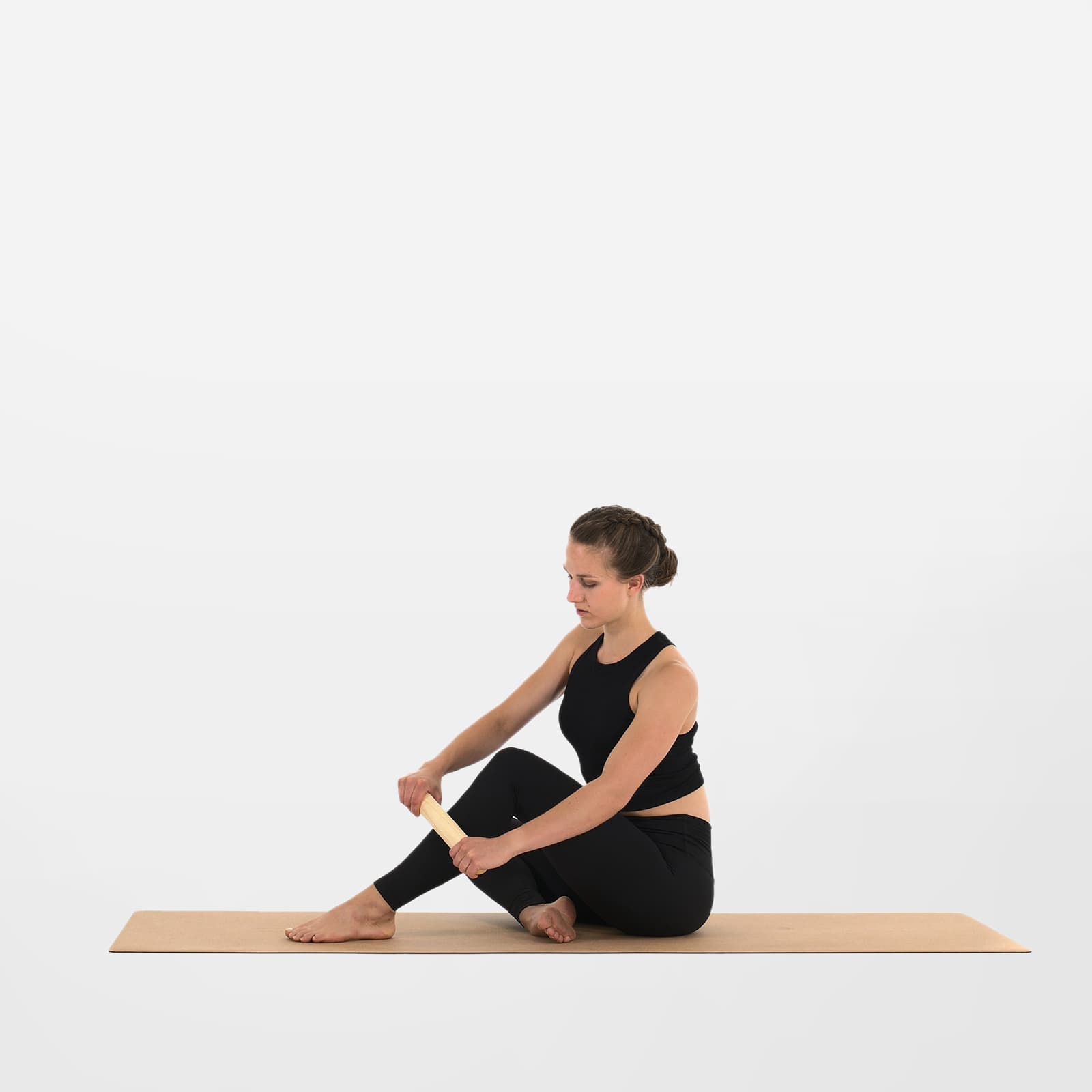 Eine Frau führt mit der rollholz Minirolle aus Eschenholz eine Selbstmassage am Schienbein zur Lockerung der Faszien durch.