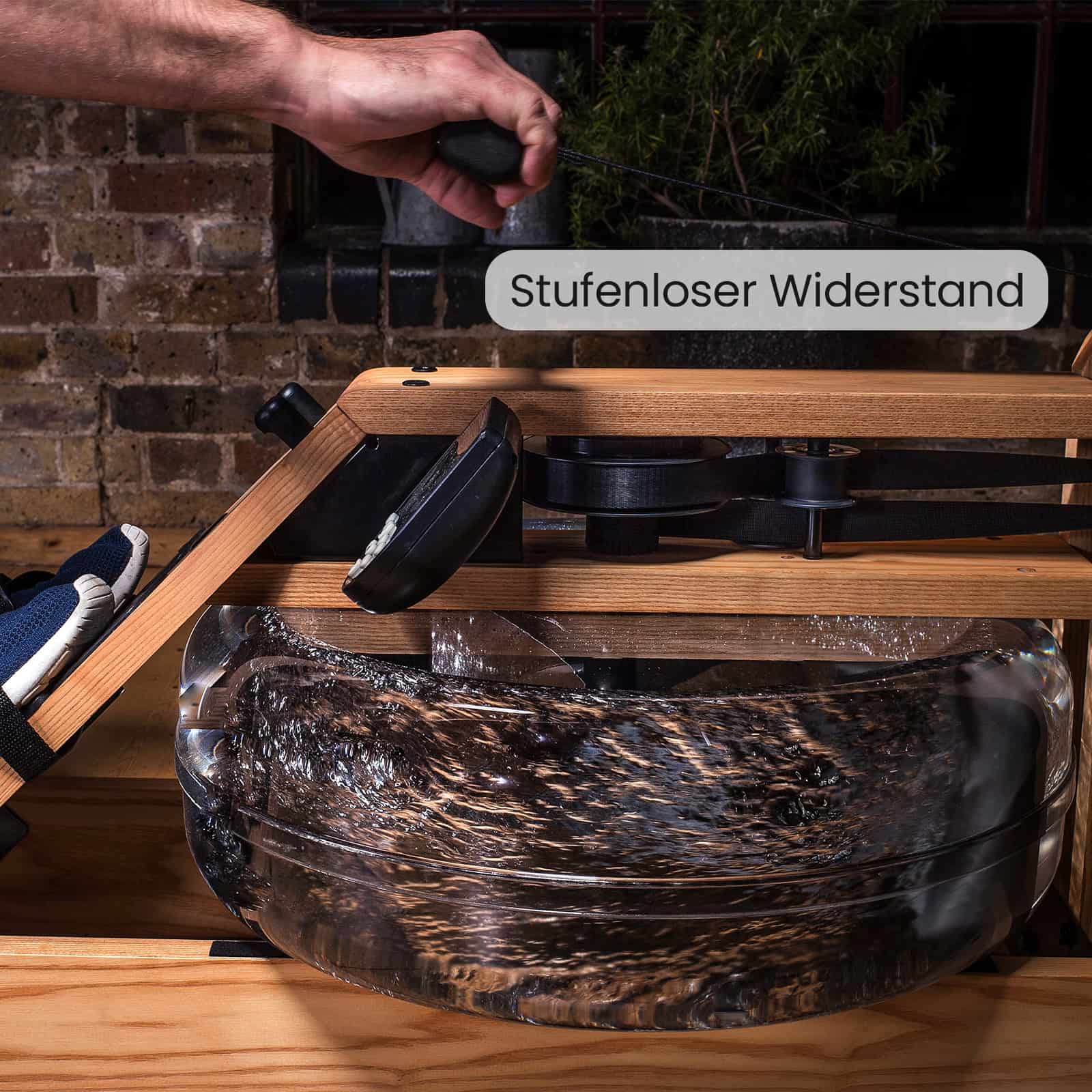 Detailaufnahme eines WaterRower Rudergeräts aus Eichenholz mit Fokus auf den Wassertank und den Text „Stufenloser Widerstand“.
