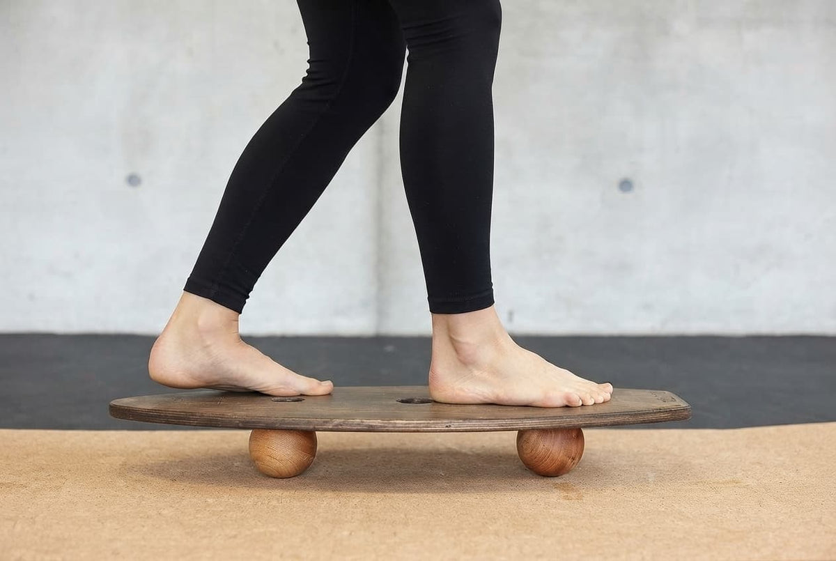 Füße im Tandemstand auf dem rollholz Balance Board mit zwei Kugeln für das Sprunggelenktraining