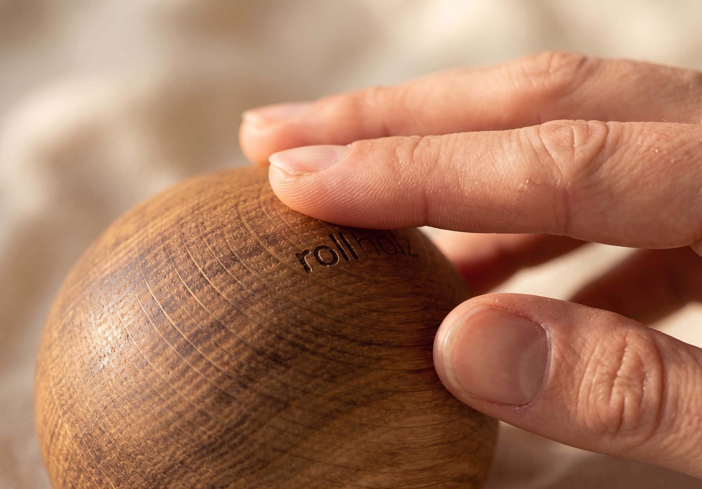 Hand hält hochwertige Holzkugel aus Holz für Faszienmassage, Fußmassage und Triggerpunktmassage – natürliche Wellness- und Regenerationsanwendung mit warmer Holzoberfläche.
