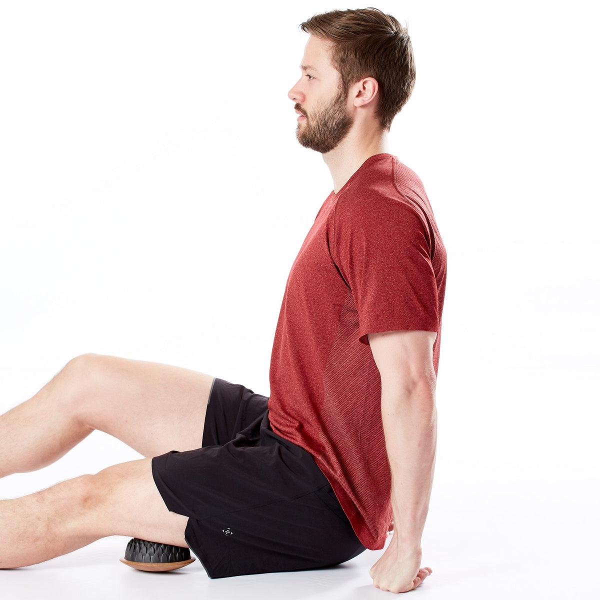 Homme assis en appui qui détend l'arrière de la cuisse avec un dôme Lotus sur base en bois placé sous la cuisse