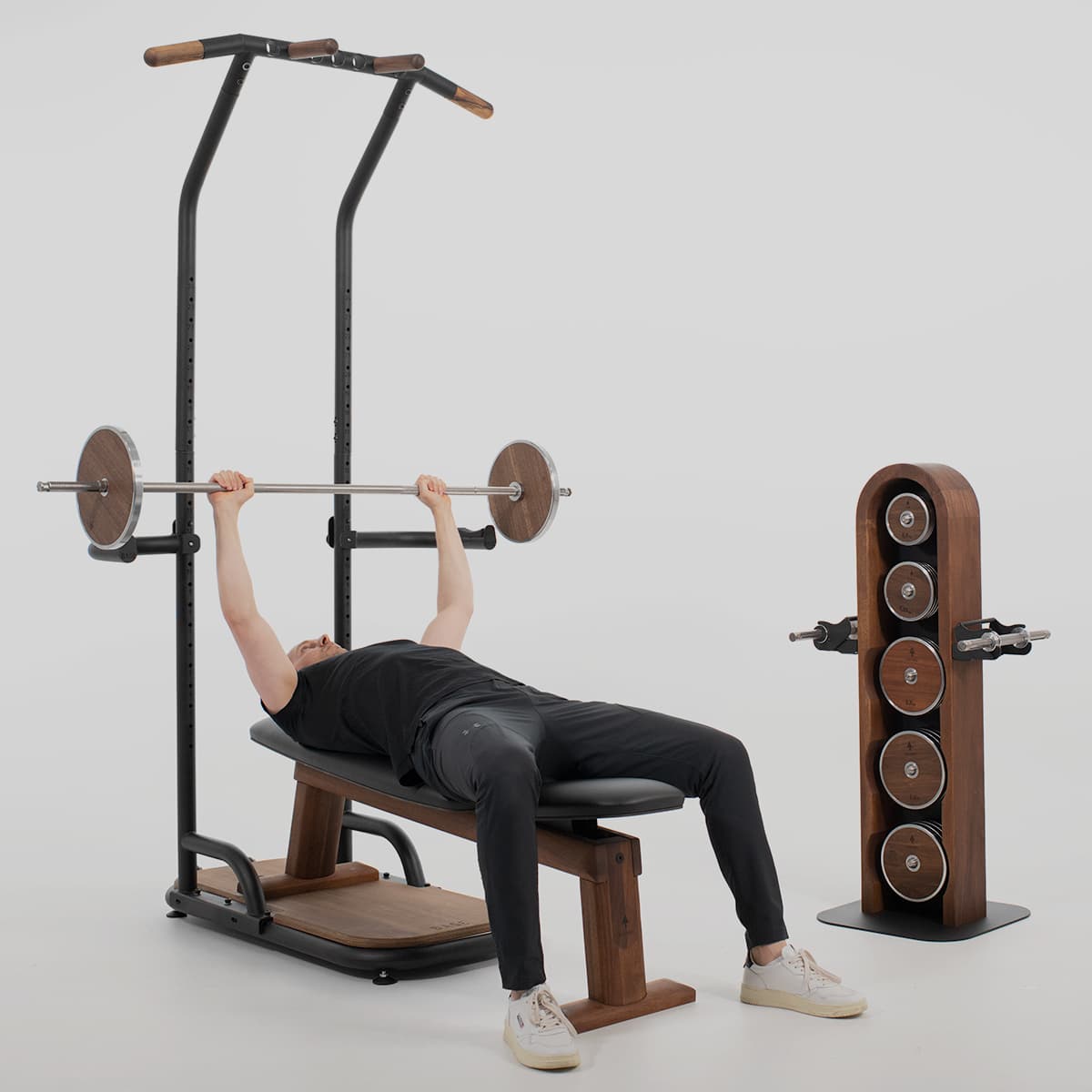 Bankdrücken an der rollholz Base Homegym-Station mit Hantelbank und Langhantel inklusive Gewichtsscheiben aus Holz.