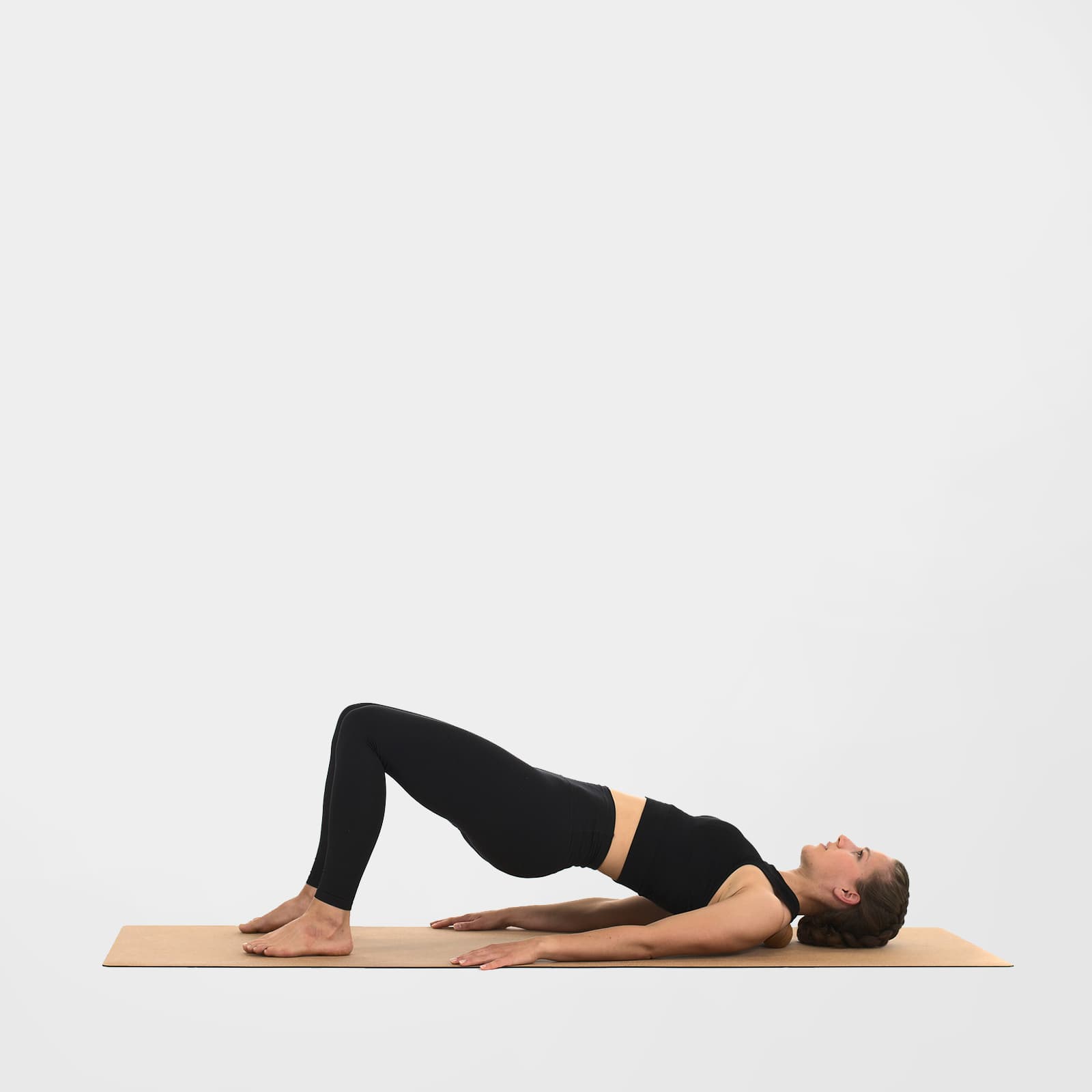 Eine Frau in der Brücken-Position auf einer Korkmatte nutzt die 7 cm rollholz Doppelkugel aus Holz zur gezielten Faszienmassage des Nackens und oberen Trapezmuskels.