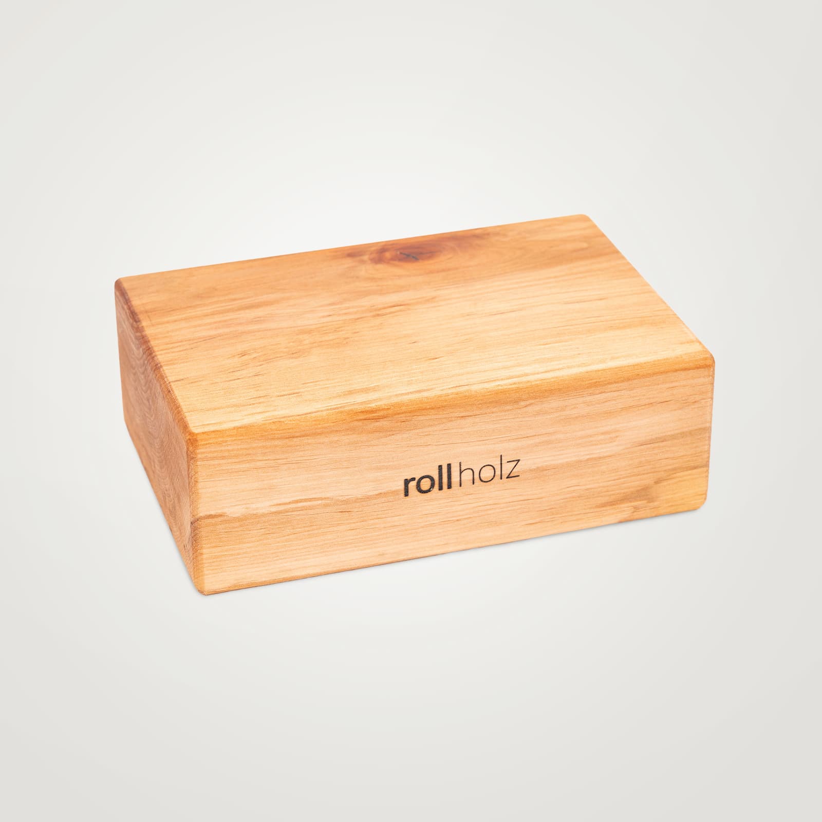 Freigestellte Ansicht eines rollholz Yogablocks aus rötlich-warmem Erlenholz mit traditionell eingebranntem Markenlogo.