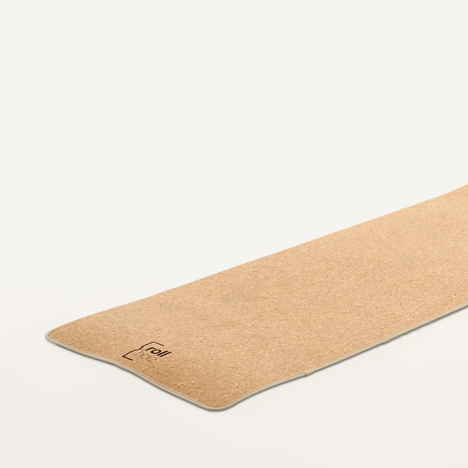 Nahaufnahme einer nachhaltigen rollholz Yogamatte aus Kork mit dezentem Logo-Branding auf hellem Grund.